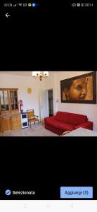 a living room with a red couch and a painting of a woman at La casetta del cacciatore 