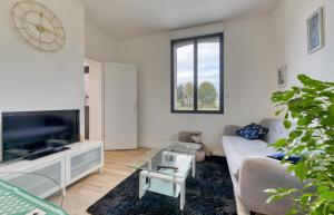 a living room with a couch and a tv at Le Hameau Paisible in Butot