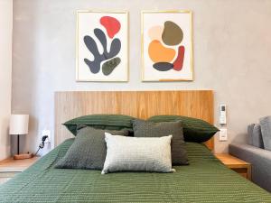 a bedroom with a green bed with two pictures on the wall at Estúdio na melhor rua do Leblon in Rio de Janeiro