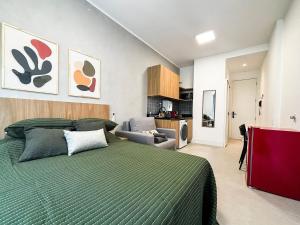 a bedroom with a green bed and a living room at Estúdio na melhor rua do Leblon in Rio de Janeiro