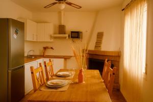 a kitchen with a wooden table with chairs and a refrigerator at Casa del Agua- Casa rural con encanto en Sierra Nevada terraza y chimenea in Abrucena