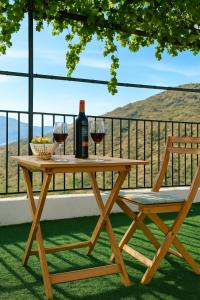 a wooden table with two glasses of wine and a chair at Casa del Agua - Escapada rural con chimenea y vistas a Sierra Nevada in Abrucena