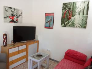 een woonkamer met een tv en een rode bank bij Mawilec, centre, plage, port, garage in Águilas