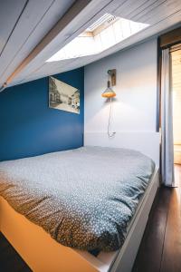 una cama en una habitación con una pared azul en L'Atelier - Gîte chaleureux et relaxant, en Saint-Hubert