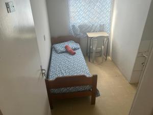 a small room with a bed and a table at Suíte 13 no centro da cidade in Uberaba