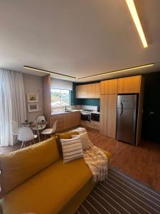 uma sala de estar com um sofá amarelo e uma cozinha em Apartamento Descolado Zona Norte em Boa Vista