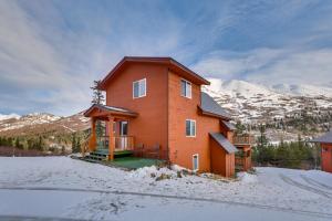 a large house in the snow with mountains in the background at Stunning Alaskan Getaway with River and Mtn Views in Eagle River