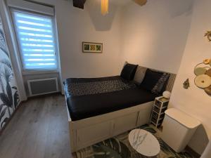 ein kleines Bett in einem Zimmer mit Fenster in der Unterkunft L'horizon De Coursan in Coursan