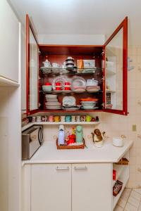 バーハ・ヴェーリャにあるBeira mar pé na areia Barra Velha com Piscinaの皿や食器がいっぱい詰まった食器棚のあるキッチン