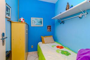 バーハ・ヴェーリャにあるBeira mar pé na areia Barra Velha com Piscinaの青い壁と小さなベッドのある寝室