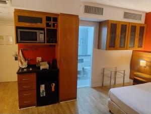 a hotel room with a bed and a cabinet with a microwave at Hotel Slaviero Grandflats Suíte Master Luxo in Sao Paulo