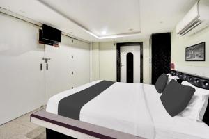 een slaapkamer met een zwart-wit bed en een tv bij Super Hotel O Mani Bhai Patel in Kota