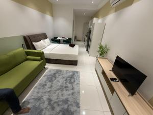 a living room with a green couch and a tv at Majestic Residance Luxury Suites By klcc in Gua Sai