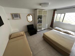 a bedroom with a bed and a chair and a window at Pousada Morada das Nações in Balneário Camboriú