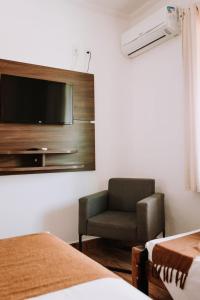Una habitación con una silla y un televisor en una pared. en Hotel Novo Horizonte, en Monte Sião
