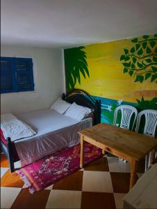 a bedroom with a bed and a table and chairs at Laverie du Soleil Surf House in Taghazout