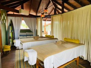 a bedroom with two beds with white curtains at Hiu Hotel in Juquei +63 photos