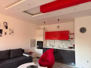 a living room with a couch and a kitchen with red cabinets at Red room in Petrovac na Mlavi +5 photos