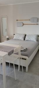 ein weißes Bett mit einem weißen Stuhl daneben in der Unterkunft Elizabeth's apartment1 in Ofrynio