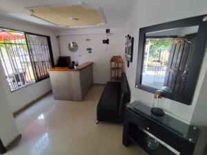 a living room with a couch and a desk and windows at Hotel Madeleine Norte in Barranquilla