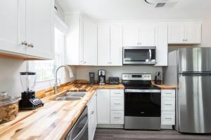 une cuisine avec des armoires blanches et un appareil noir dans l'établissement Newly Updated Cottage in the Heart of KDH, à Kill Devil Hills