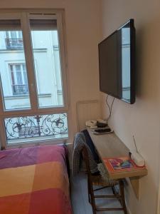 a bedroom with a desk with a television on the wall at Cosy renovated little nest in historic MONTMARTRE in Paris
