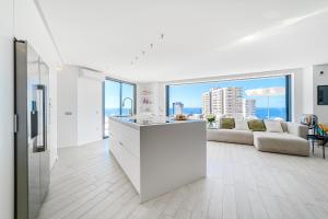 a white kitchen and living room with a couch at White Haven in Adeje