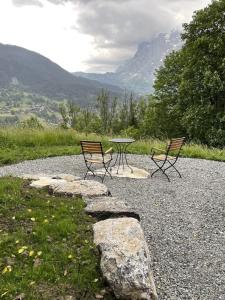 two chairs and a table on a gravel road at Ferienhaus Chalet Simeli in Grindelwald