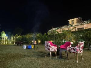 een groep stoelen die 's nachts op het gras zitten bij Corbett Mid Forest House - 1Min Walk to River & Jungle Safari in Rāmnagar