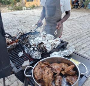 a person is cooking food on a grill at Kio Farm Retreat in Kiserian +61 photos