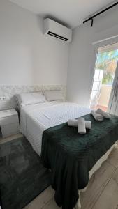 a white bedroom with a bed with two towels on it at Apartamento Benalbeach in Benalmádena