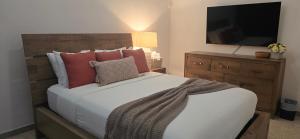 a bedroom with a bed and a dresser with a television at Boho Chic Relaxing Space in Fajardo