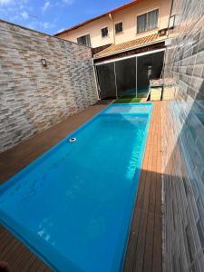 a large blue swimming pool in front of a building at Jacara Beach House - Seu Refúgio in Serra