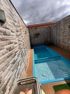a swimming pool in the side of a brick wall at Jacara Beach House - Seu Refúgio in Serra