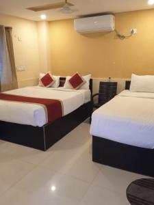 ein Hotelzimmer mit zwei Betten und einem Fenster in der Unterkunft The Royal Inn 1 in Visakhapatnam
