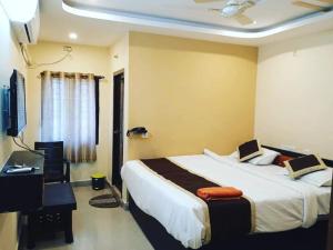 ein Schlafzimmer mit einem Bett, einem Schreibtisch und einem Fernseher in der Unterkunft The Royal Inn 1 in Visakhapatnam