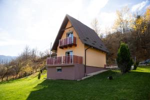 a house with a balcony on a grassy field at Planinska kuća S&I in Dejčići