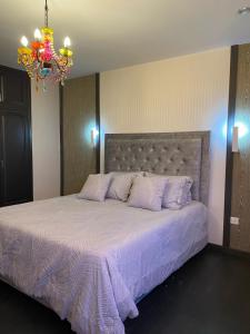 a bedroom with a large bed with purple sheets and a chandelier at Mi refugio chiquinquireño in Chiquinquirá