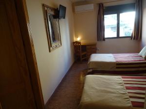 Una habitación de hotel con dos camas y una ventana. en Hotel Mesón el Castillo, en Bañeres de Mariola