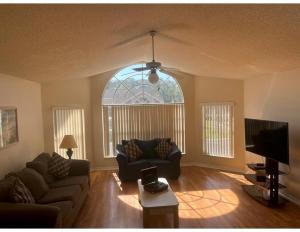 Cozy and Spacious Apartment near Disney Kissimmee في كيسيمي: غرفة معيشة مع أريكة وتلفزيون