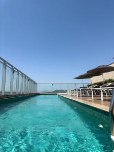 einen Pool mit blauem Wasser und Sonnenschirmen in der Unterkunft Promenade Fusion Itaguaí in Itaguaí + 15 Fotos
