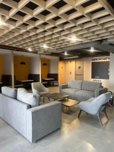 a living room with couches and tables and a screen at Aparta estudio Zona Norte Bogotá in Bogotá