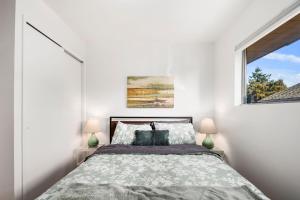 a white bedroom with a bed and a window at Shorewood Retreat -10 mins to Seattle-private yard in Burien