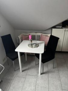 a white table with two chairs and a pink candle on it at Dein Zuhause auf Zeit! in Güster