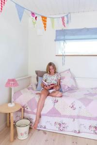 a girl sitting on a bed reading a book at OGO730-Vikbolandet-Vaerldens-Aende-46 in Arkösund