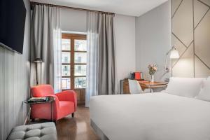 a hotel room with a bed and a red chair at NH Collection León Plaza Mayor in León