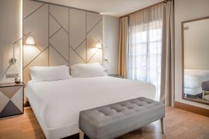 a bedroom with a large white bed and a large window at NH Collection León Plaza Mayor in León +44 photos