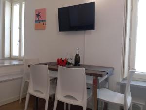 mesa de comedor con sillas blancas y TV de pantalla plana en Miramare4, en Ceriale