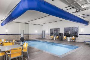 ein großes Becken mit Stühlen, einem Tisch und einer blauen Rutsche in der Unterkunft GLō Best Western Dawley Farms In Sioux Falls in Sioux Falls