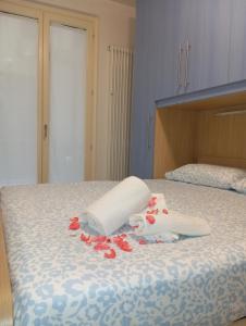 Una cama con dos toallas y flores rojas. en Miramare4, en Ceriale